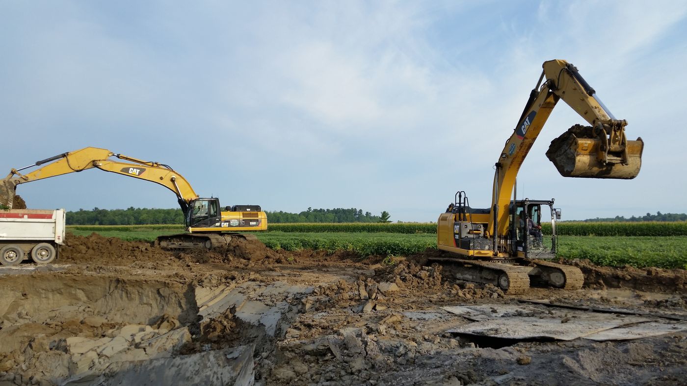 Deux pelles hydrauliques en excavation, l'une chargeant un camion-benne